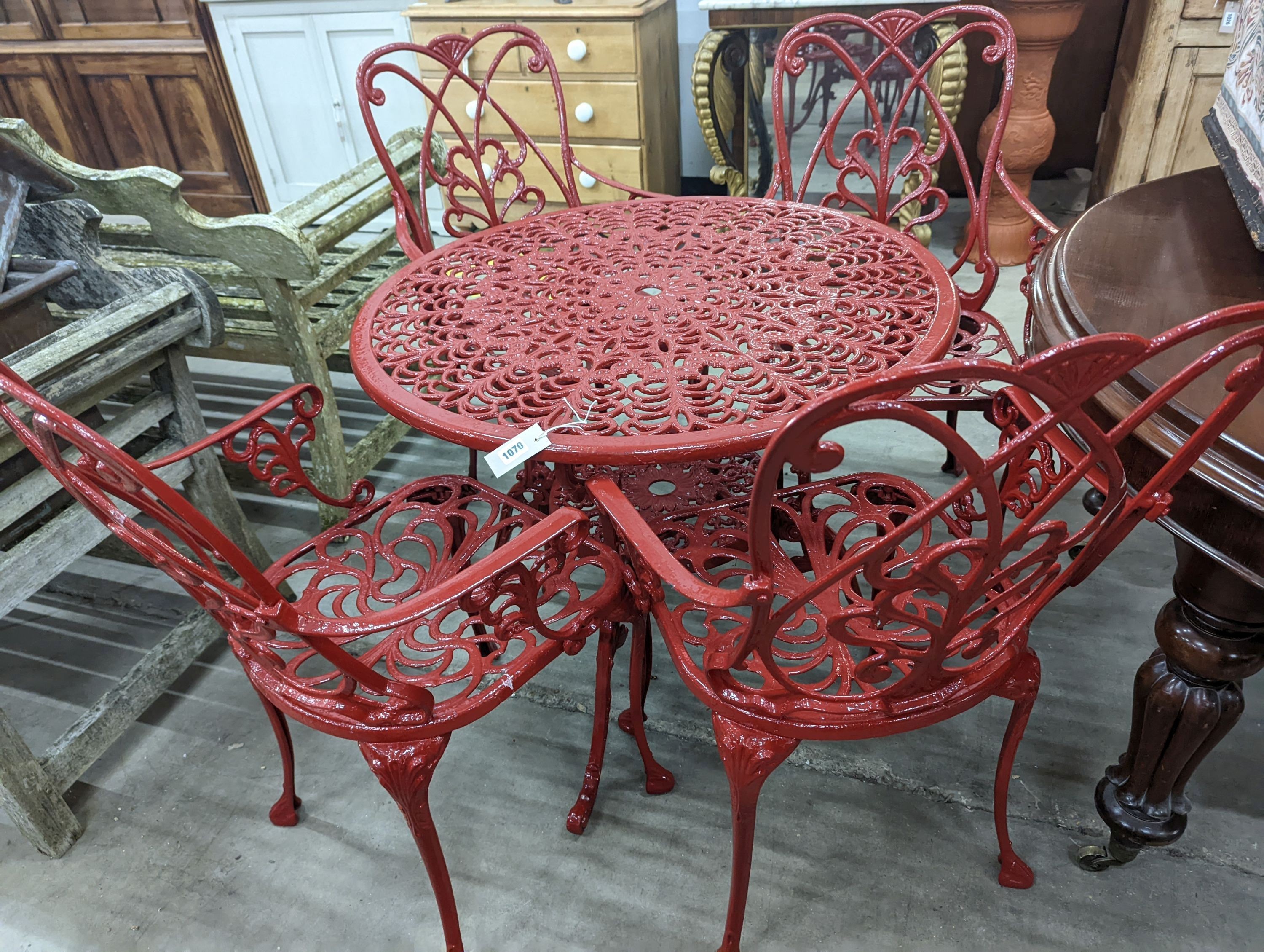 A circular red painted aluminium garden table, diameter 86cm, height 67cm together with four matching chairs